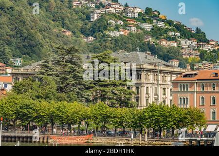 Como, ITALIA - 4 agosto 2019: Appartamenti, ville, alberghi sulle verdi montagne boscose vicino al Lago di Como. Bellissima città italiana di Como. Caldo sole s Foto Stock