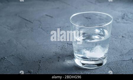 Bicchiere d'acqua con una pillola frizzante. Recupero da mal di testa Foto Stock