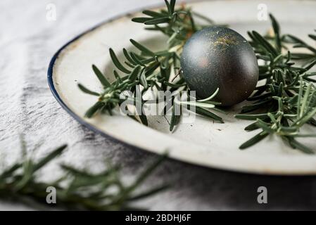 Pasqua. Sfondo dell'uovo colorato naturalmente. Focus selettivo su piatto vintage con uova e rosmarino. Foto Stock