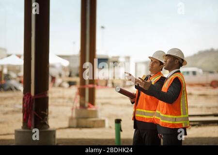 Due colleghi di lavoro che discutono di un progetto in un cantiere. Foto Stock