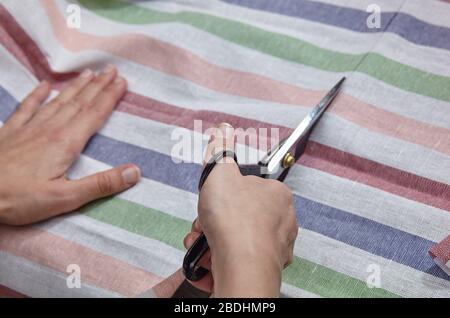 Sarto ragazza taglia tessuto a righe con forbici Foto Stock