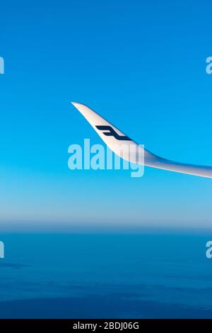 Finlandia Helsinki 2 MAR 2020 Logo blu delle compagnie aeree Finnair sull'ala dell'aereo di fronte al cielo blu e all'orizzonte blu della Terra durante il tramonto Foto Stock