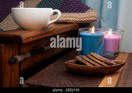 Accogliente scena di biscotti al cioccolato, caffè, candele e sedia in legno, rustico Foto Stock