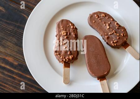 Gelato alla vaniglia ricoperto di cioccolato sul piatto bianco Foto Stock