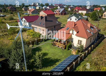 Vista aerea di una nuova casa autonoma con i pannelli solari, acqua radiatori di riscaldamento sul tetto e vento a turbina di potenza sul verde giardino. Foto Stock