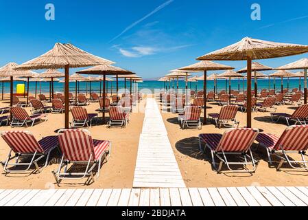 Mediterraneo Mare tropicale vacanza destinazione estiva. Acque oceaniche turchesi, cielo blu, lettini per il tempo libero vuoti, cannucce. Arina sabbia beac vuoto Foto Stock