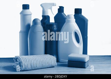 Bottiglie colorate di prodotti per la pulizia, spugna e straccio per la pulizia della casa su sfondo bianco. Colorazione in blu classico Foto Stock