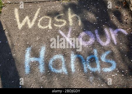 Vancouver, Canada, 07 aprile 2020. Il disegno colorato di gesso di un bambino sul marciapiede ricorda ai passanti di lavarsi le mani durante la pandemia COVD-19. Foto Stock