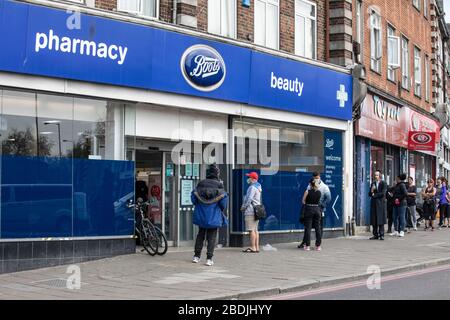 Le persone si accodano al di fuori di una farmacia Boots a Stamford Hill, nel nord di Londra, durante il blocco COVID-19, Londra, Inghilterra, Regno Unito Foto Stock