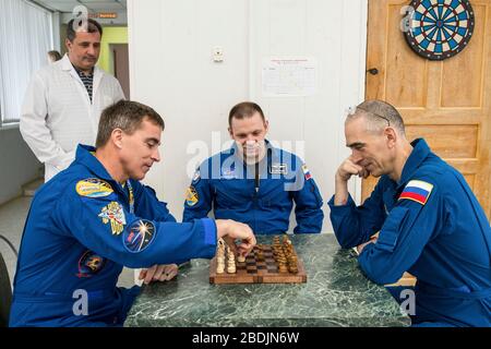 Spedizione 63 membri dell'equipaggio Russi Ivan Vagner, centro, Anatoly Ivanishin, destra, di Roscosmos e americano Chris Cassidy della NASA, a sinistra, giocare una partita di scacchi durante il tempo di inattività al Cosmonaut Hotel al Baikonur Cosmodrome 1 aprile 2020 a Baikonur, Kazakhstan. Soyuz MS16 lancerà alla Stazione spaziale Internazionale portando le tre il 9 aprile per una missione di sei mesi e mezzo al laboratorio orbitante. Foto Stock