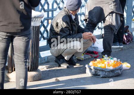 Un vecchio fornitore che vende macchine per spremere il succo di limone. La gente passa intorno all'uomo che ha una sigaretta in bocca. Foto Stock