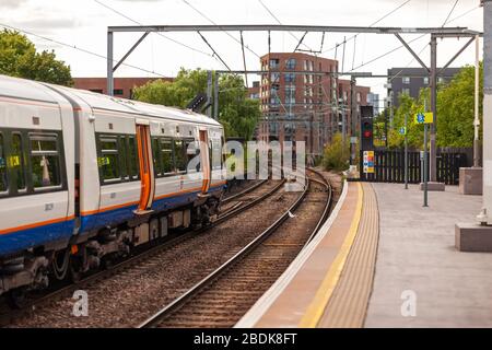 I treni sotterranei e terrestri sono parte integrante del sistema di transito Englands, come questi passeggeri che attendono alla stazione di Camden Road a Londra. Foto Stock