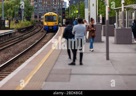 I treni sotterranei e terrestri sono parte integrante del sistema di transito Englands, come questi passeggeri che attendono alla stazione di Camden Road a Londra. Foto Stock