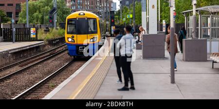 I treni sotterranei e terrestri sono parte integrante del sistema di transito Englands, come questi passeggeri che attendono alla stazione di Camden Road a Londra. Foto Stock