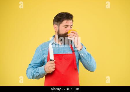 Cucina sana. Preparazione di insalate fresche. Chef professionista nel grembiule rosso. La cucina è il suo hobby. Uomo barbuto in uniforme cuoco. Casalinga sicura preparare il pomodoro. Uomo maturo tenere coltello e verdure. Foto Stock