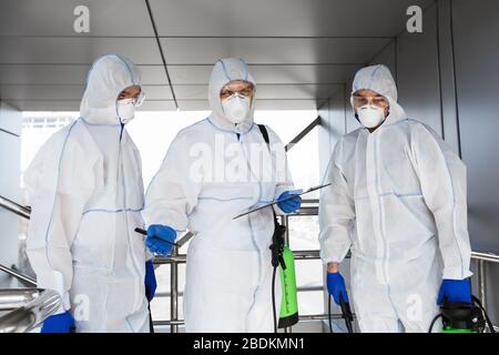 Team di virologi in abiti hazmat fare piano di disinfezione Foto Stock