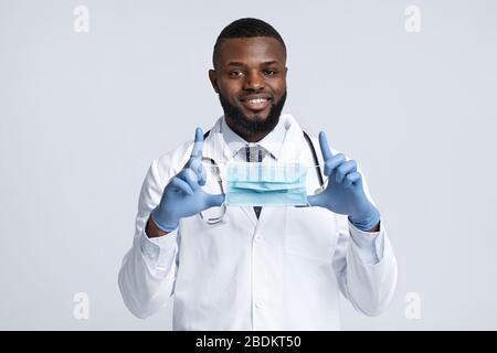 Terapista africano maschile positivo indossando maschera facciale Foto Stock