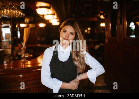 Ritratto di giovane attraente cameriera bionda caucasica all'ingresso del cafe' Foto Stock
