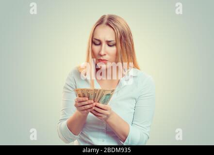 Closeup ritratto riuscito giovane business donna camicia bianca conteggio soldi dollari fatture in mano isolato verde sfondo giallo. Emozione positiva fa Foto Stock