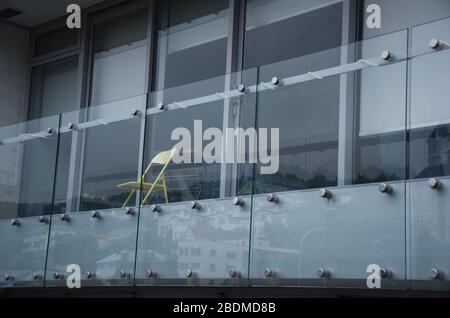 WELLINGTON, NUOVA ZELANDA - 4 aprile 2020: Sedia gialla seduta sul balcone di un edificio vuoto Foto Stock