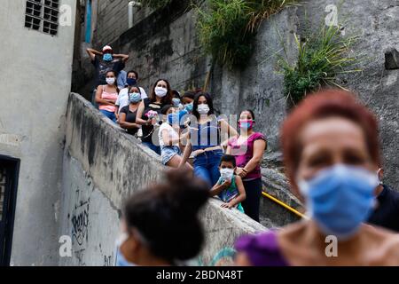 Caracas, Venezuela. 8 aprile 2020. Giovani e bambini con maschere in attesa della figura di Gesù "Nazareno de San Pablo" durante la celebrazione della settimana Santa. La processione annuale, in cui i pellegrini camminano tradizionalmente attraverso la città insieme, non avrà luogo quest'anno a causa delle restrizioni di uscita contro la diffusione del coronavirus. La Chiesa cattolica ha scelto di guidare la figura religiosa attraverso la capitale, in modo che i fedeli possano vederla da casa. Credit: Rafael Hernandez/dpa/Alamy Live News Foto Stock