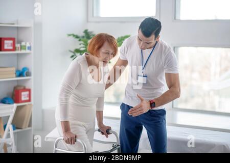 Istruttore giovane professionista che dirige il paziente durante l'esercizio Foto Stock