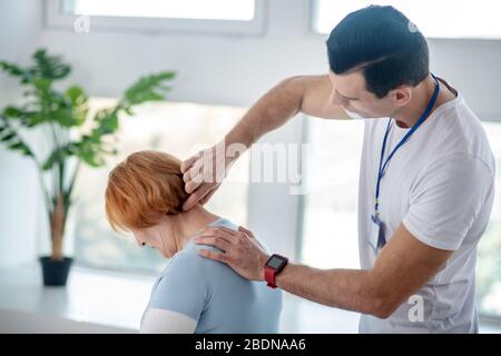 Bel terapista esperto che tocca il collo dei suoi pazienti Foto Stock