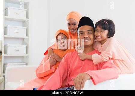 Felice ritratto di famiglia malese in abiti tradizionali durante Hari Raya. Stile di vita familiare malese a casa. Foto Stock