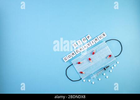 L'iscrizione FERMA CORONAVIRUS su sfondo blu. Maschere mediche protettive, pillole e siringhe. Coronavirus, Covid-19. Protezione contro i virus, c Foto Stock