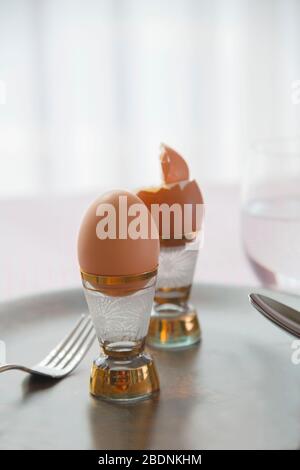 primo piano di due uova sode su piatto scuro in ceramica su uno sfondo tovaglia a scacchi, concetto alimentare dieta Foto Stock