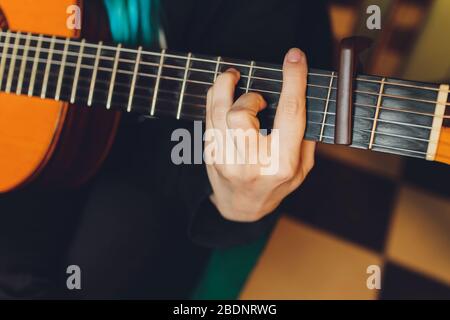 Primo piano chitarra acustica nelle mani di un musicista in camera oscura Foto Stock
