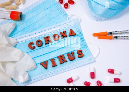 Equiment medico, maschera e pillole intorno alle lettere di parole corona virus su sfondo bianco. Concetto di allarme per la protezione da pandemia virale Foto Stock