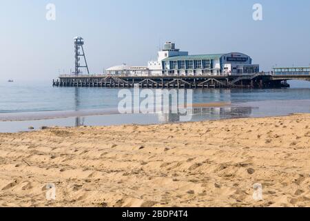 Bournemouth, Dorset Regno Unito. 9 aprile 2020. Tempo nel Regno Unito: I visitatori sono invitati a stare lontani dalla popolare località balneare di Bournemouth con le previsioni di un glorioso e soleggiato fine settimana di Pasqua. Una calda giornata di sole, mentre la gente va al mare per fare il loro esercizio quotidiano, la maggior parte aderendo alle restrizioni Coronavirus per le distanze sociali, come le spiagge sono principalmente vuote. Il molo chiuso mostra il messaggio Essential Travel Only (solo viaggio essenziale). Credit: Carolyn Jenkins/Alamy Live News Foto Stock