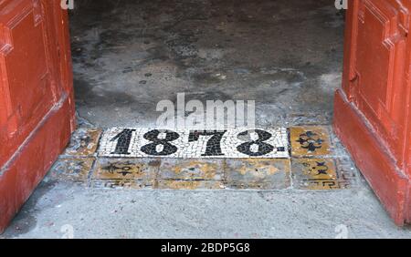 Iscrizione 1878 su un pavimento in cemento calpestato all'ingresso di un vecchio edificio a San Pietroburgo, Russia Foto Stock