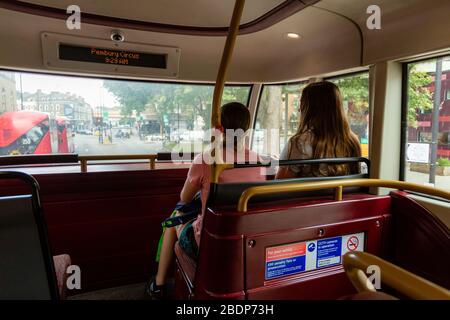 Due ragazze siedono sul davanti del ponte superiore di un autobus a due piani a Londra, Inghilterra. Foto Stock