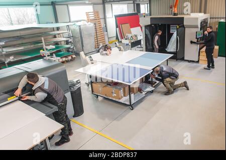 Un grande gruppo di operatori addetti alla stampa lavora in una sala stampa digitale e in un ufficio di stampa con molti tipi diversi di macchine Foto Stock