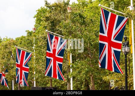 Grandi versioni dell'Union Jack appendono dalle aste di bandiera lungo il Mall nella City of Westminster, Greater London prima di un grande evento. Foto Stock