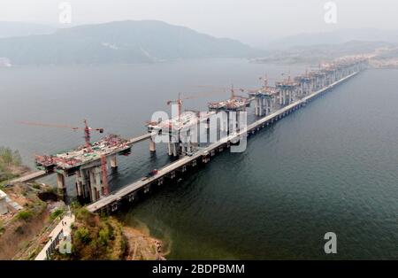 Zhengzhou. 9 Aprile 2020. La foto aerea scattata il 9 aprile 2020 mostra il sito di costruzione di un ponte della superstrada Mianchi-Yuanqu sul Fiume giallo, provincia centrale di Henan della Cina. Il ponte è un'importante superstrada interprovinciale che collega le province di Shanxi e Henan, con una lunghezza di progetto di 1,757 metri e una larghezza di 33 metri. Il progetto dovrebbe essere completato e aperto al traffico entro la fine del 2020. Credit: Zhu Xiang/Xinhua/Alamy Live News Foto Stock