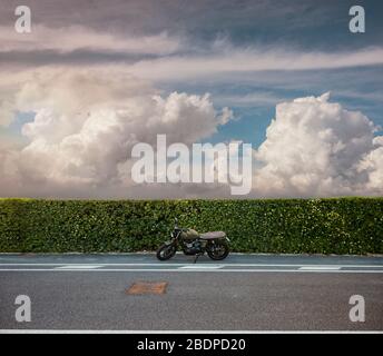 Una motocicletta è parcheggiata sul lato di una strada Foto Stock