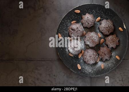 Muffin al cioccolato da dessert su un piatto nero. Sfondo grigio in cemento Foto Stock