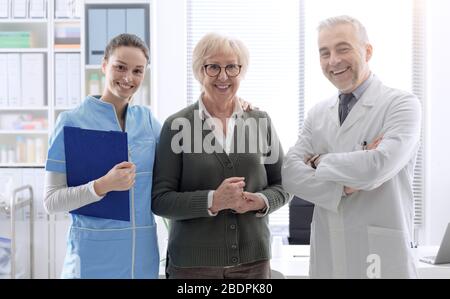 Sorridente paziente di sesso femminile senior in posa con personale medico professionale presso la clinica: Assistenza e concetto di assistenza sanitaria Foto Stock