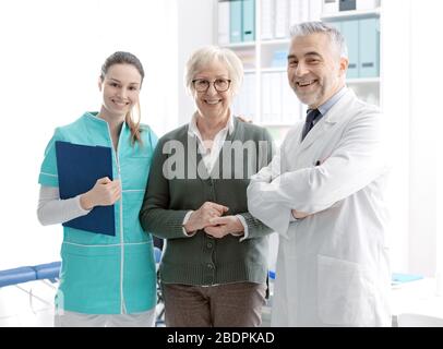 Sorridente paziente di sesso femminile senior in posa con personale medico professionale presso la clinica: Assistenza e concetto di assistenza sanitaria Foto Stock