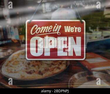 Un segno di affari che dice 'come in We're Open' sulla vetrina del negozio di pizza. Foto Stock