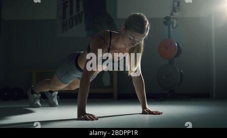 Donna muscolare atletica che fa push-up in palestra, fitness e sport concetto Foto Stock