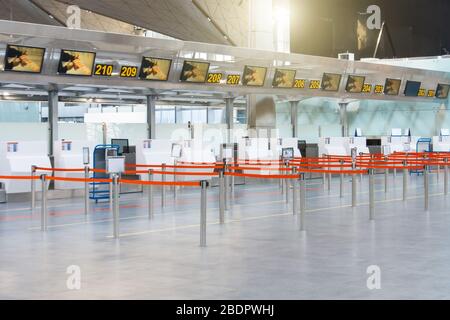 Percorsi vuoti delimitati da un nastro rosso ai banchi check-in e al check-in bagagli al terminal passeggeri Foto Stock