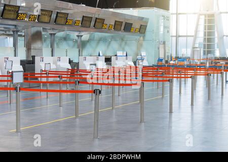 Percorsi vuoti delimitati da un nastro rosso ai banchi check-in e al check-in bagagli al terminal passeggeri Foto Stock