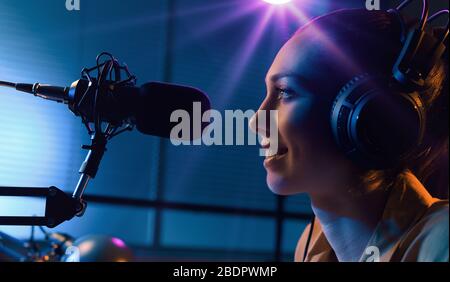 Giovane affascinante radio dj che lavora in studio, sta parlando del microfono, l'intrattenimento e la comunicazione concetto Foto Stock