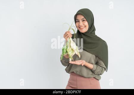 donna con ketupat su sfondo bianco. donna musulmana hijab su eid ramadan con torta di riso piatto tradizionale Foto Stock