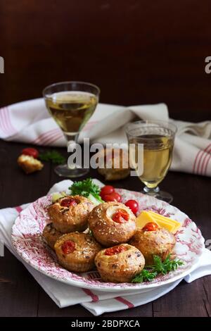Muffin con formaggio, formaggio casolare e pomodori, verdure e formaggi serviti con vino. Foto Stock
