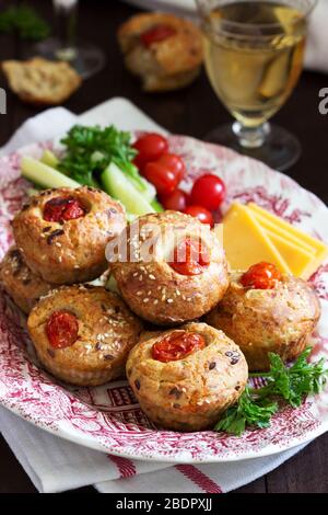 Muffin con formaggio, formaggio casolare e pomodori, verdure e formaggi serviti con vino. Foto Stock